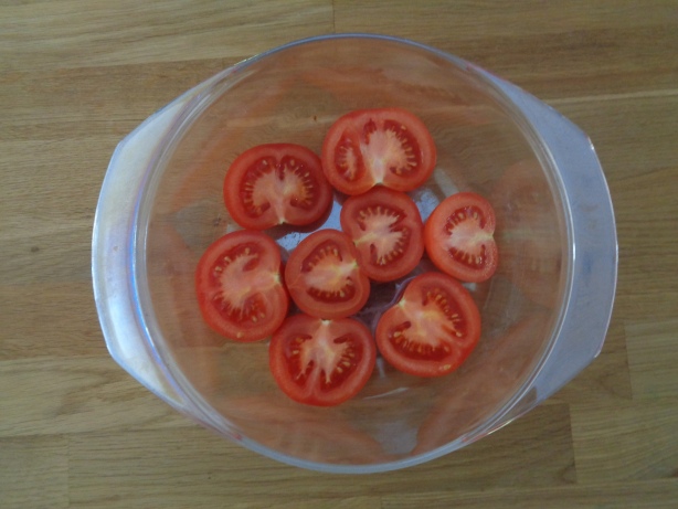 Cut the tomatos in half and put them into the baking dish